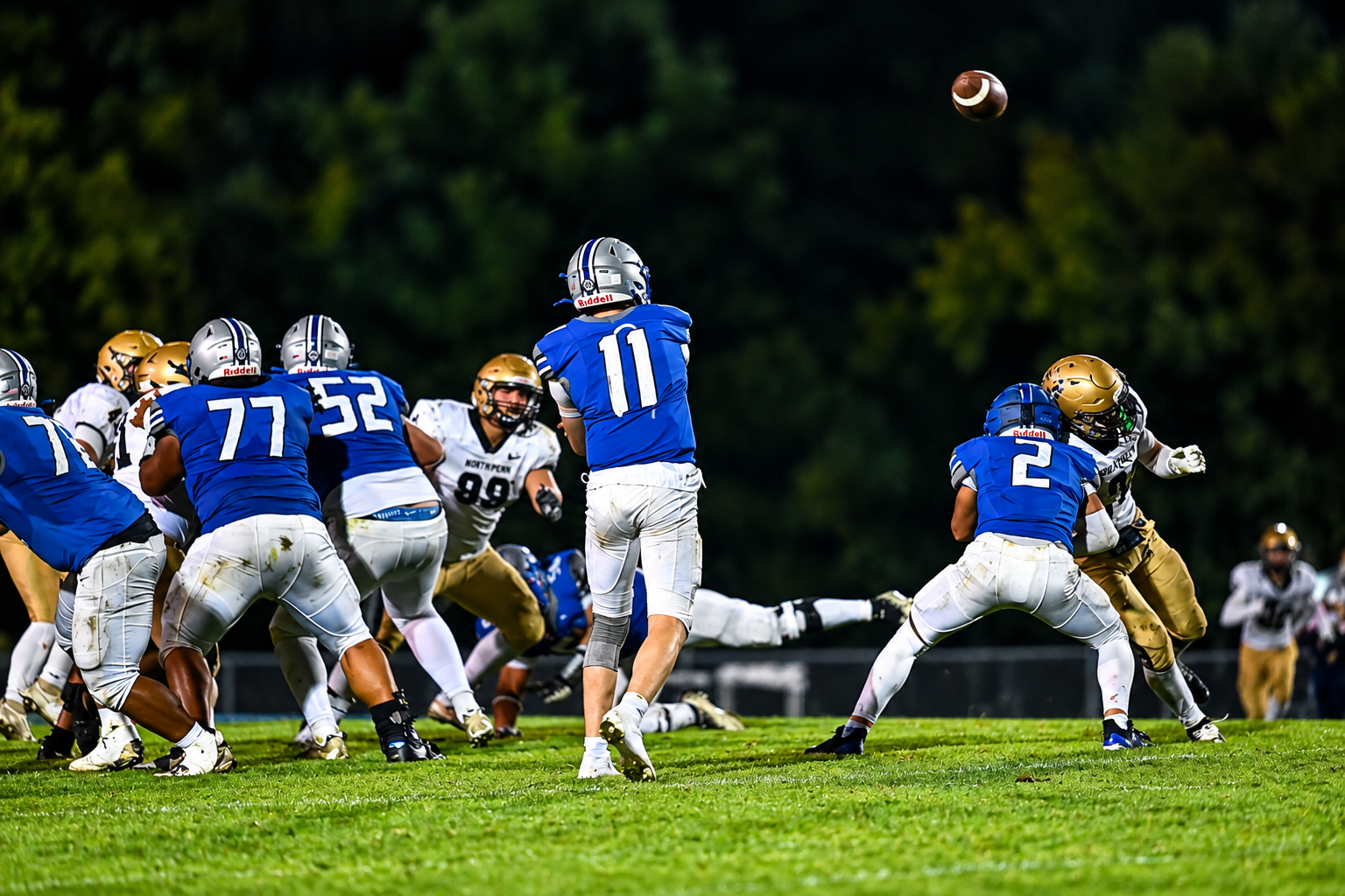 High school quarterback throwing a pass at night